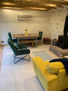 a living room with a wooden table and a yellow couch at The Nest at Walnut Cottage in Burrowbridge