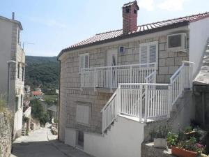 a brick house with a white railing and a balcony at One bedroom apartment in Povlja in Povlja