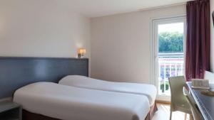 duas camas num quarto de hotel com uma janela em The Originals City, Hôtel Le Louisiane, Belfort Sud (Inter-Hotel) em Andelnans