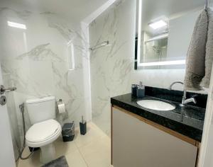 La salle de bains est pourvue de toilettes, d'un lavabo et d'un miroir. dans l'établissement Apartamento na melhor localização de Foz, à Foz do Iguaçu