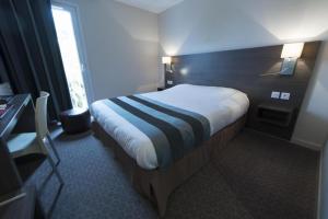 a hotel room with a bed and a desk at The Originals City, Hôtel Le Louisiane, Belfort Sud (Inter-Hotel) in Andelnans