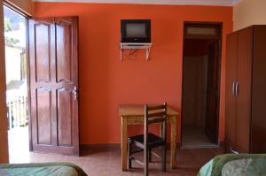 Habitación con mesa y TV en la pared. en Hostal Coronel Pedro Arraya, en Tupiza