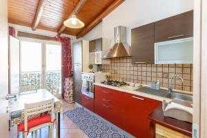 een keuken met rode kasten en een groot raam bij A casa di Maria in Catania