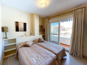 een slaapkamer met een bed en een groot raam bij Apartamento acogedor de 2 dormitorios a solo 150 m de la playa Sabinillas, Manilva in San Luis de Sabinillas