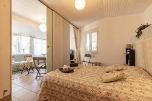 een slaapkamer met een bed en een woonkamer bij Maisonnette La Chaleureuse in Jonzac