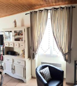 um quarto com uma cadeira, um armário e uma janela em Maison Des Lys em Jonzac