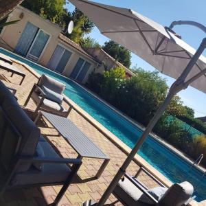 um guarda-sol e cadeiras junto a uma piscina em L'Abri Côtier, villa avec piscine au coeur des vignes em Caux
