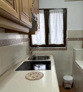 eine kleine Küche mit einem Waschbecken und einem Fenster in der Unterkunft El Desván de Gredos in Navarredonda de Gredos