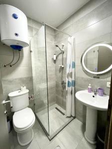 a bathroom with a shower and a toilet and a sink at Stone Bridge Hotel in Peje