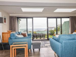 a living room with blue chairs and a view of the ocean at Cormorant in Holywell Bay