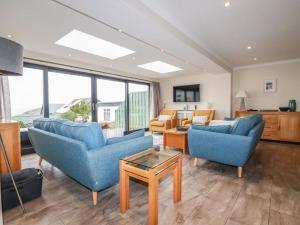 a living room with two blue chairs and a table at Cormorant in Holywell Bay