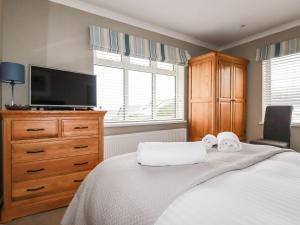 a bedroom with a bed with a tv and a dresser at Cormorant in Holywell Bay
