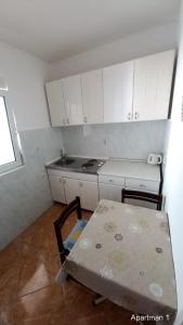a kitchen with a table and a stove and white cabinets at Apartments Dikan in Herceg-Novi