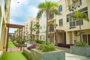 a courtyard of a building with palm trees and grass at 2 BHK Independent Flat at Ganpati Infinity Vrinadvan in Mathura