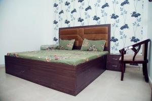 マトゥラーにある2 BHK Independent Flat at Ganpati Infinity Vrinadvanの木製ベッド1台(椅子付)