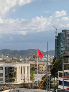 una bandera roja está volando delante de un edificio en Urban Rooms en Tirana