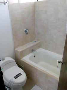 y baño con aseo, bañera y lavamanos. en Suite Sumapaz Hotel en Melgar