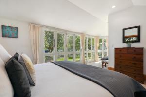 a bedroom with a bed and a dresser and windows at Fendalton Villa - Christchurch Holiday Home in Christchurch