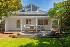 a white house with a table and chairs on a patio at Fendalton Villa - Christchurch Holiday Home in Christchurch