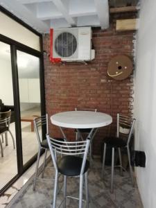 een tafel en stoelen in een kamer met een bakstenen muur bij Balcarce Suits PB in Bell Ville