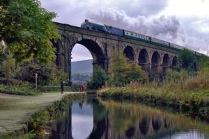 a train on a bridge over a river at Wharmton luxury apartment in Dobcross