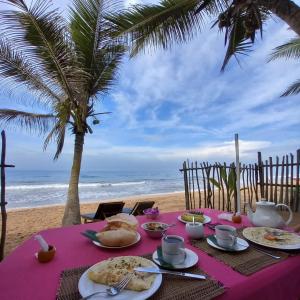 a table with plates of food on the beach at Arcade Beach Hotel in Induruwa