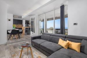 Lux Apartment SKY VIEW في رييكا: غرفة معيشة مع أريكة رمادية وطاولة