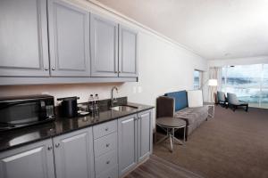 a kitchen with white cabinets and a living room with a couch at Niagara Falls Marriott on the Falls in Niagara Falls