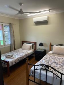 a bedroom with two beds and a lamp and a window at Cheerful city house in Cairns