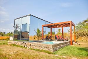 a glass house with chairs and a pool at Sojourn Cabins in Anomabu