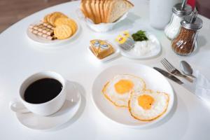 a white table with a plate of eggs and a cup of coffee at Hotel NOMAD in Aktobe