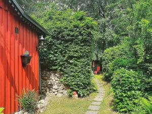 un camino de jardín junto a un edificio rojo en Holiday home TJÖRNARP VII en Tjörnarp