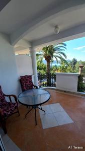 a patio with a table and chairs and a palm tree at Apartments Dikan in Herceg-Novi