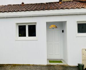a white house with a white door and windows at Le cosy in Labarde