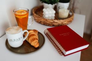 a table with a cup of coffee and croissants and a book at RABA RESORT - Domki i Apartamenty pod Krakowem in Gdów