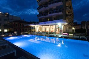 una piscina di fronte a un edificio di notte di Hotel Adlon a Lido di Jesolo