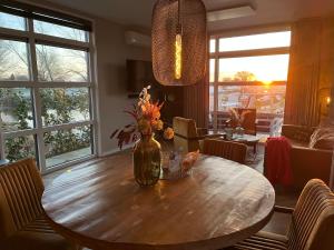 a dining room table with a vase of flowers on it at Luxus Chalet Hafenblick in Lathum