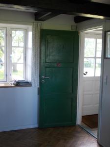 eine grüne Tür in einem Zimmer mit zwei Fenstern in der Unterkunft Paradiset Holiday House in Blans