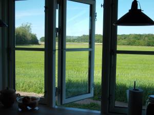 ein offenes Fenster mit Blick auf ein Grasfeld in der Unterkunft Paradiset Holiday House in Blans