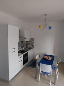 una cucina con armadi bianchi e tavolo blu di Appartamento Memorie a Otranto