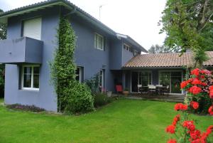 niebieski dom z ogródkiem z czerwonymi kwiatami w obiekcie Villa 8 personnes proche d'Hossegor au bord du Golf de Pinsolle w mieście Soustons