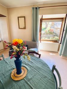 a table with a blue vase with flowers on it at La maison de Marie in Junhac +5 photos