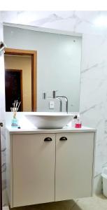 a bathroom with a white sink and a mirror at Quarto Jaraguá/São Luís in Jaraguá do Sul