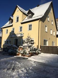 ein großes gelbes Haus mit einem Weihnachtsbaum davor in der Unterkunft Ferienwohnung Körber in Gößweinstein
