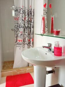 La salle de bains est pourvue d'un lavabo blanc et d'une serviette rouge. dans l'établissement La Jacaranda, à Casarabonela