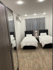 a bedroom with two beds and a mirror at Caprios motel in Al Qasţal