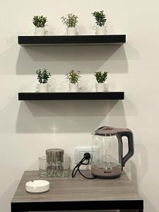 a tea kettle on a table with plants on a shelf at Caprios motel in Al Qasţal