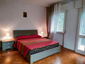 Il Terrazzo Sulle Dolomiti في Cibiana: غرفة نوم بسرير وبطانية حمراء ونافذة