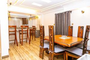a dining room and kitchen with a wooden table and chairs at MacCinray Villa Kisii in Kisii