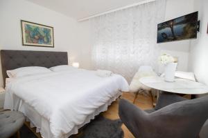 - une chambre blanche avec un grand lit et deux chaises dans l'établissement Apartman BARBARA, à Vinkovci